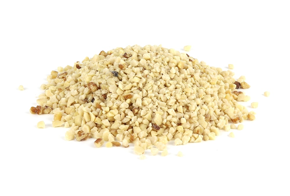 A heap of finely chopped nuts is spread against a white background. The nuts are small and uniformly cut, varying slightly in color, with shades ranging from light beige to light brown.